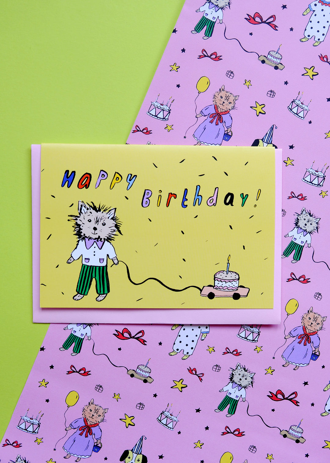 Birthday card with a cat illustration on a pink background with birthday-themed patterns.