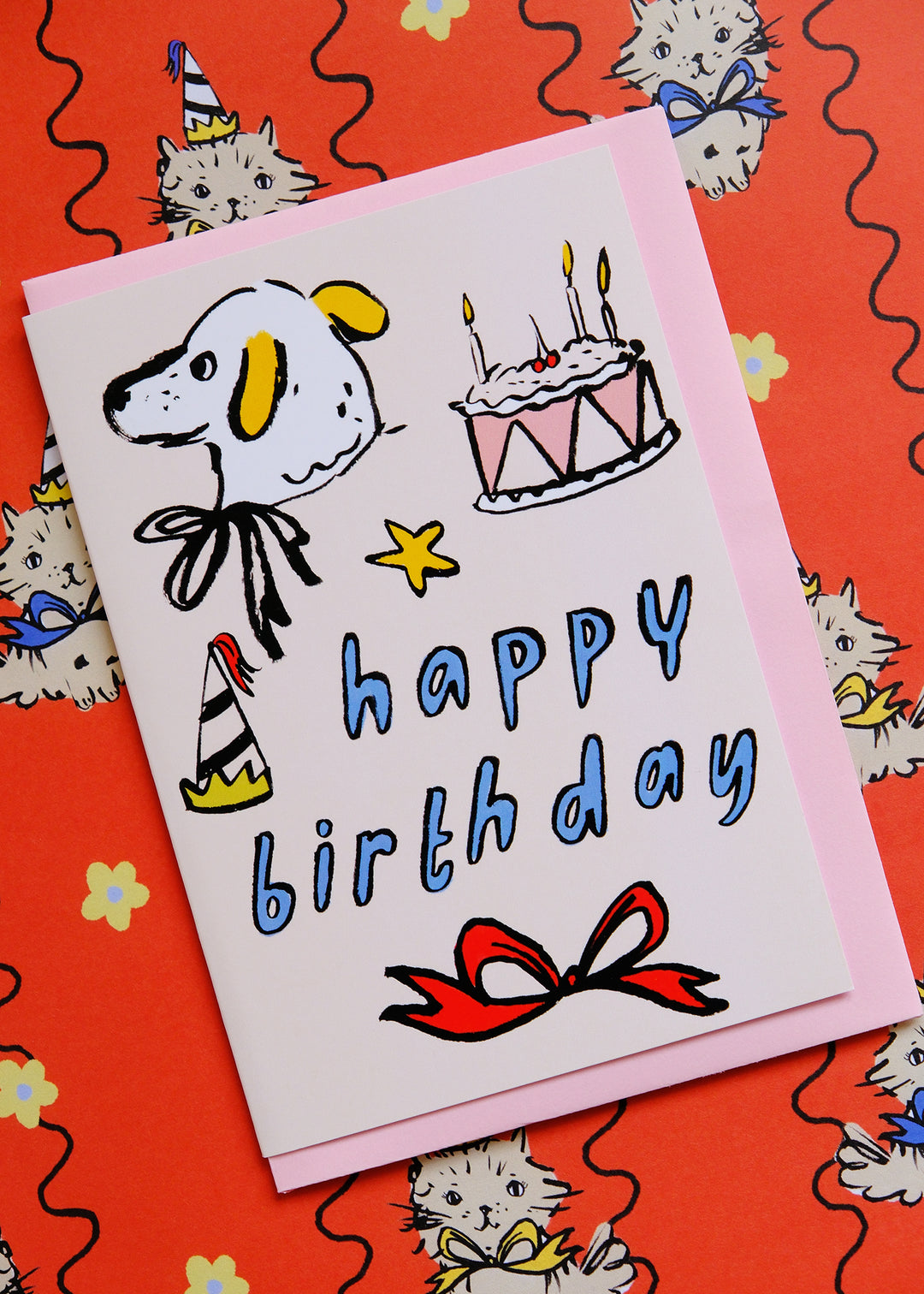Birthday card with cartoon dog, cake, and 'Happy Birthday' text on a red background with cat illustrations.