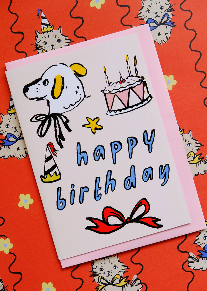 Birthday card with cartoon dog, cake, and 'Happy Birthday' text on a red background with cat illustrations.